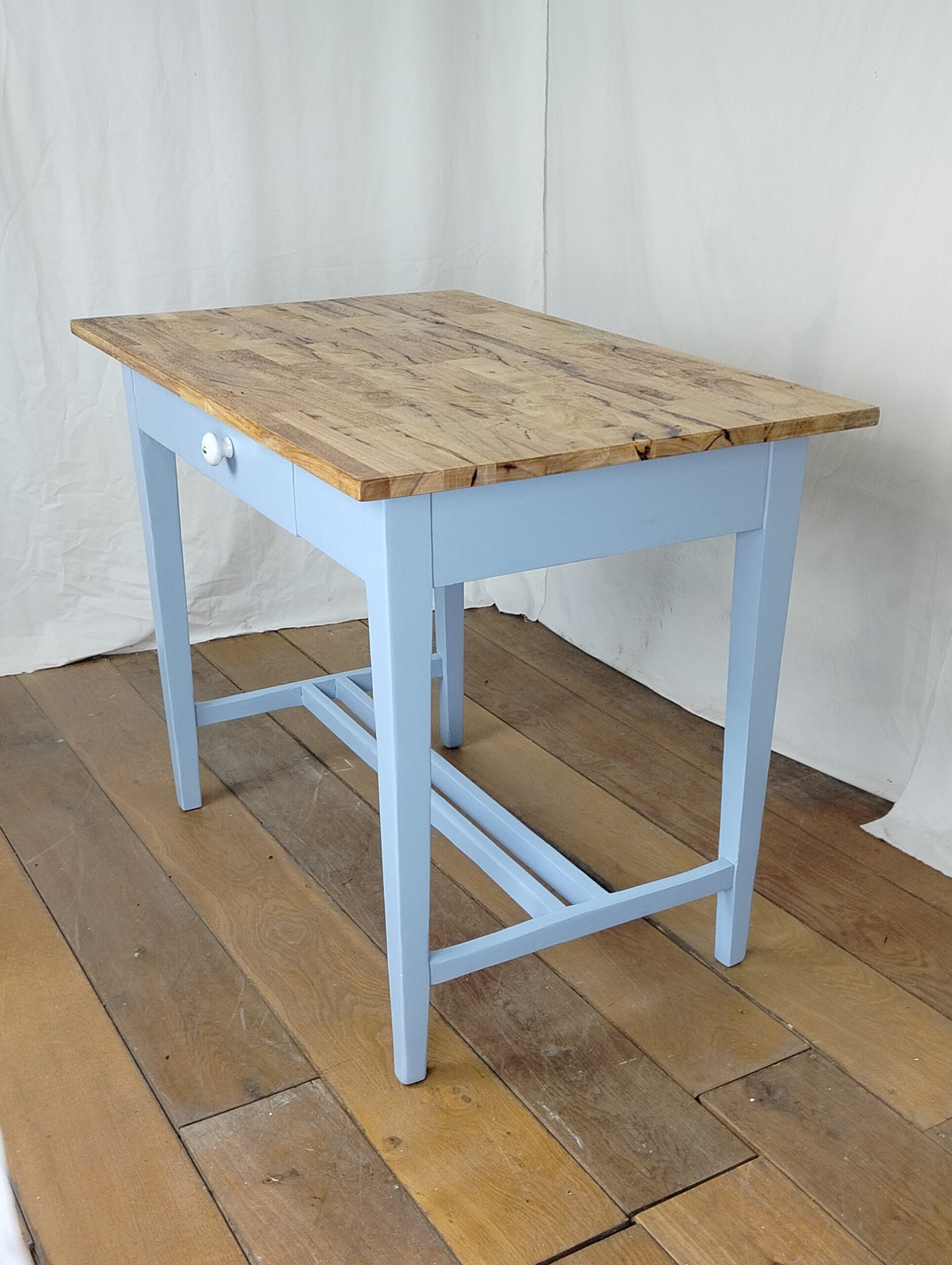 Menší zrenovovaný dřevěný jídelní stůl v barvě baby blue s přírodní deskou