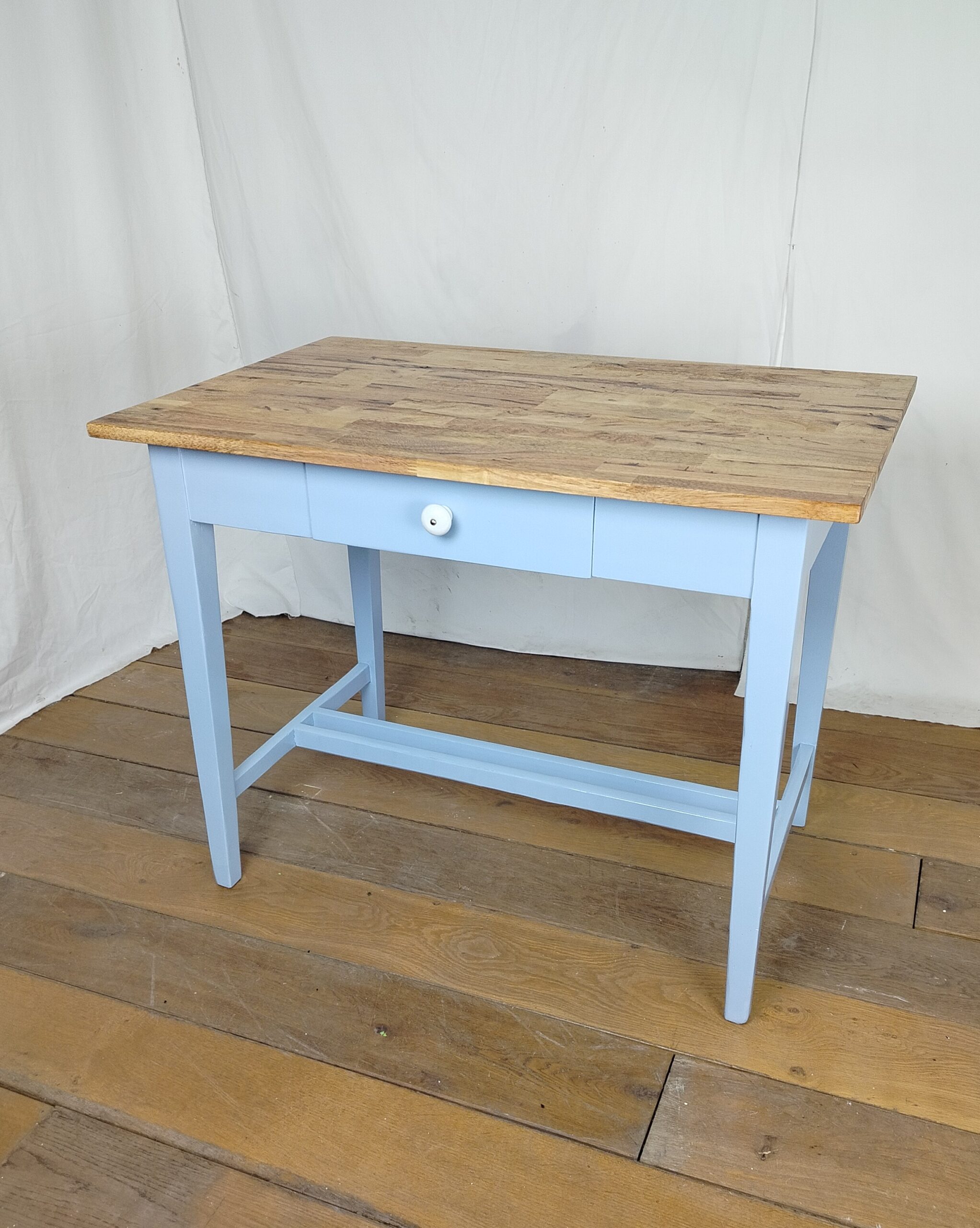 Menší zrenovovaný dřevěný jídelní stůl v barvě baby blue s přírodní deskou